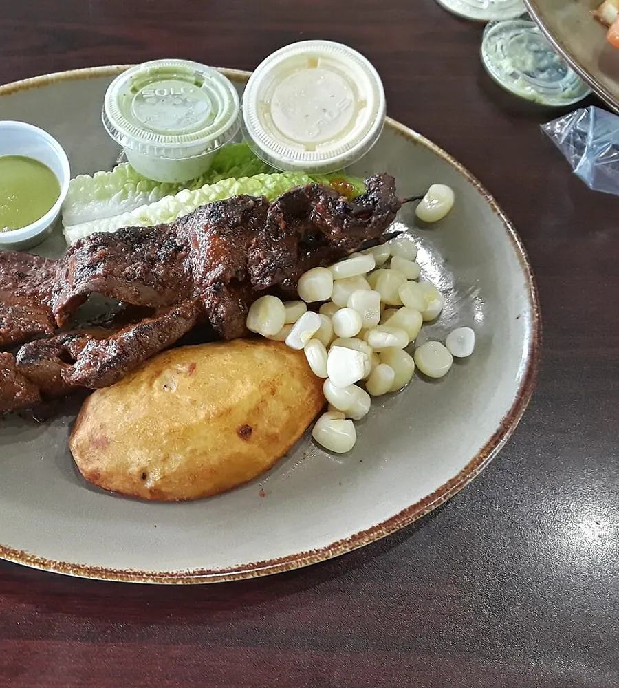Anticuchos con papa dorada, choclo y cremas